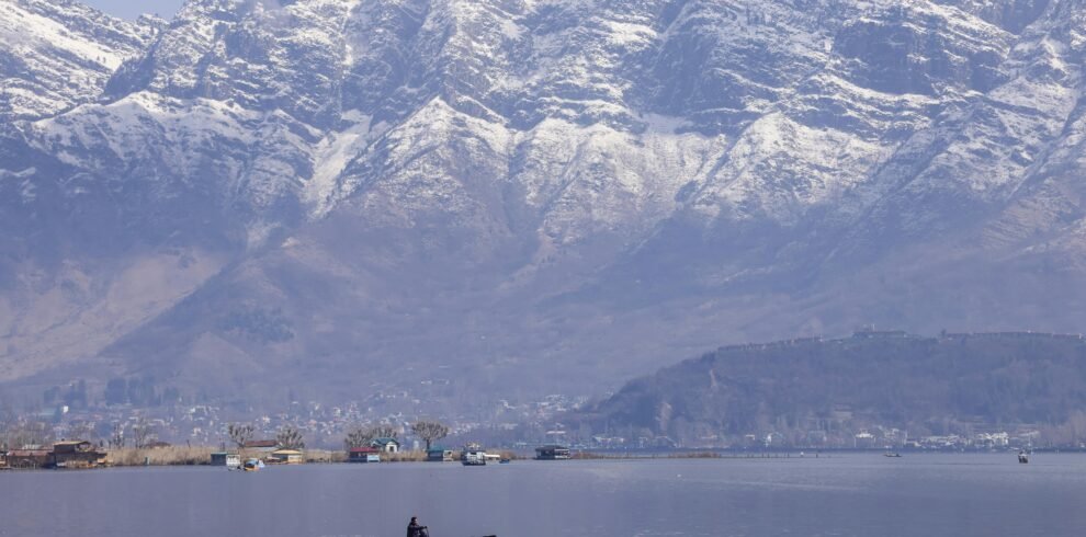 Tranquil scene of a boat on Dal Lake with snow-capped Zabarwan mountains in Srinagar.