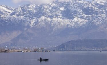 Tranquil scene of a boat on Dal Lake with snow-capped Zabarwan mountains in Srinagar.