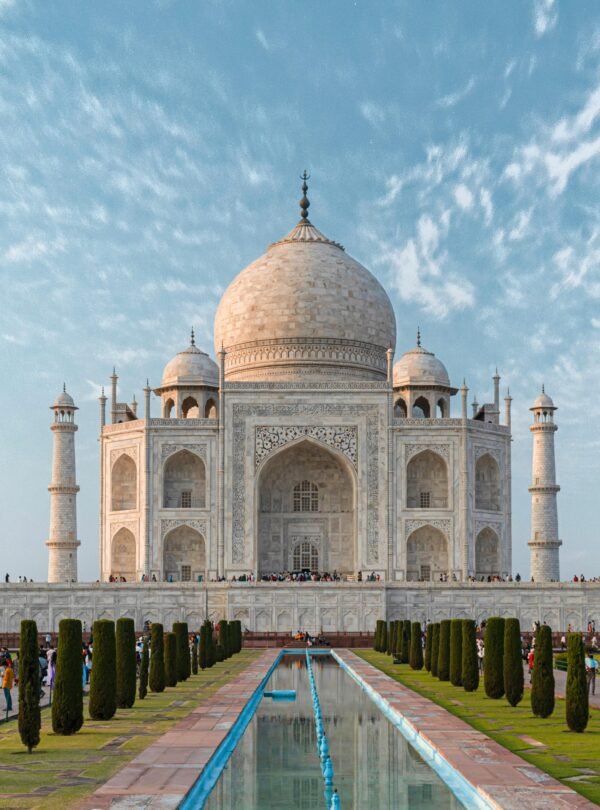 Front view of the Taj Mahal, showcasing its iconic architecture against a blue sky.