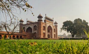 Stunning view of Mughal architecture with lush green surroundings at sunrise.